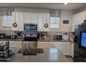 Well-appointed kitchen featuring sleek countertops, stainless steel appliances, white cabinetry, and a tiled backsplash at 16648 W Jenan Dr, Surprise, AZ 85388