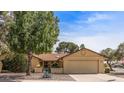 Traditional-style home with desert landscaping, mature trees, and a two-car garage provides great curb appeal at 19503 N 142Nd Dr, Sun City West, AZ 85375