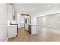 Open kitchen and living area with a kitchen island with seating, white cabinetry, stainless steel appliances and light countertops at 21074 N 58Th St, Phoenix, AZ 85054