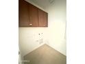 Laundry room with tiled floors, white walls, and upper cabinetry for storage at 25180 W Wayland Dr, Buckeye, AZ 85326