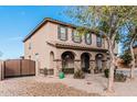 Charming two-story home featuring an inviting front porch with stone pillars and desert landscaping with decorative tree at 6208 N 78Th Dr, Glendale, AZ 85303