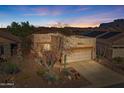 Charming home featuring desert landscaping, a two-car garage, and a warm, inviting facade nestled against a beautiful desert mountain backdrop at 9796 E Stone Cir Ln, Gold Canyon, AZ 85118