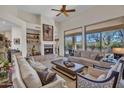 Spacious living room with a cozy fireplace, ceiling fan, and outdoor views through large windows at 10040 E Happy Valley Rd # 249, Scottsdale, AZ 85255