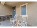 Inviting front porch featuring rocking chairs, stone accents, and a welcoming entrance at 10822 W Taylor St, Avondale, AZ 85323