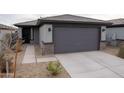 Charming single-story home featuring a gray garage door, stone accents, and desert landscaping at 17353 W Via De Luna Dr, Surprise, AZ 85387