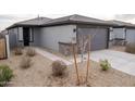 Attractive single-story home with gray exterior, complemented by desert landscaping and a spacious driveway at 17353 W Via De Luna Dr, Surprise, AZ 85387