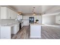 Bright kitchen featuring an island with quartz countertops, white cabinets, and stainless steel appliances, flowing into an open living space at 38234 N 15Th Ave, Phoenix, AZ 85086