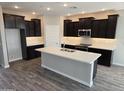 Modern kitchen with dark cabinetry, white quartz countertops, stainless steel appliances and gray wood flooring at 1191 E Ridgerock St, Casa Grande, AZ 85122