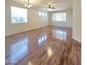 Spacious living room featuring wood floors, large windows, ceiling fan and neutral wall colors at 15232 W Edgemont Ave, Goodyear, AZ 85395