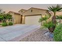 Home exterior with a spacious driveway and a two-car garage, surrounded by desert landscaping and palm trees at 15829 W Bonitos Dr, Goodyear, AZ 85395