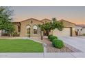 Inviting home featuring lush green lawn, desert landscaping, and a spacious driveway leading to the garage at 15829 W Bonitos Dr, Goodyear, AZ 85395