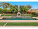 Beautiful backyard pool featuring a stone waterfall, fireplace, and lush greenery at 1918 W Medinah Ct, Anthem, AZ 85086