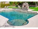 Sparkling pool with stone waterfall feature, lounge chairs, and serene backyard at 1918 W Medinah Ct, Anthem, AZ 85086