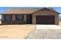 A charming single-story home featuring a two-car garage and desert landscaping at 27411 N 256Th Dr, Wittmann, AZ 85361