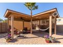 Inviting covered patio with a hammock, ceiling fan, and comfortable seating with brick pavers at 42578 W Rosalia Dr, Maricopa, AZ 85138