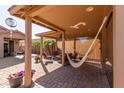 Covered outdoor patio features a hammock, ceiling fan, and comfortable seating with brick pavers at 42578 W Rosalia Dr, Maricopa, AZ 85138