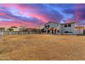 Spacious backyard with a white fence, lawn, and a two-story home with string lights at dusk at 31301 N Sunflower Way, San Tan Valley, AZ 85143