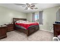 A carpeted main bedroom boasts a ceiling fan and large window for ample natural light at 45 S 238Th Dr, Buckeye, AZ 85396