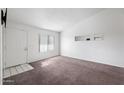 This vacant living room has tan carpet, white walls, and a front door leading to the exterior at 461 W Holmes -- # 342, Mesa, AZ 85210