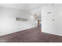 A vacant living room with white walls, tan carpet, and a ceiling fan. Has a minimalist design at 461 W Holmes -- # 342, Mesa, AZ 85210