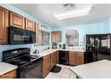 Traditional kitchen with wooden cabinets, black appliances, and a breakfast bar opening to another room at 10510 W Louise Dr, Peoria, AZ 85383