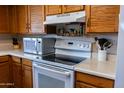 Close-up of a kitchen with modern white appliances, white countertop, and wooden cabinets at 1213 N Raven --, Mesa, AZ 85207