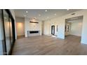 Open-concept living room featuring wood floors, a modern fireplace, and large windows for natural light at 13302 E Buckskin Trl, Scottsdale, AZ 85255