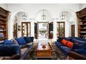 Elegant living room with white arches, dark wood shelving, and blue couches leading to a bright outdoor space at 6221 E Vista Dr, Paradise Valley, AZ 85253