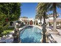 Expansive backyard pool area with statues, a bright red door and lush landscaping, perfect for relaxing and entertaining at 6221 E Vista Dr, Paradise Valley, AZ 85253