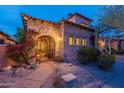 Stone entryway with wrought iron gate, lush landscaping, and bougainvillea at 7442 E Golden Eagle Cir, Gold Canyon, AZ 85118