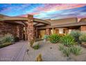 Striking front exterior showcasing natural stone accents, desert plants and an arched entry at 9962 E Groundcherry Ln, Scottsdale, AZ 85262