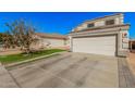 The home features a spacious driveway, manicured lawn, and a charming facade with a two car garage at 12818 W Pershing St, El Mirage, AZ 85335