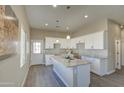Bright kitchen features white cabinets, granite countertops, a large island, and modern pendant lighting at 14951 S Capistrano Rd, Arizona City, AZ 85123