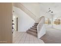 Bright entryway featuring high ceilings, tile floors, and a carpeted staircase with white railings at 15825 S 1St Ave, Phoenix, AZ 85045