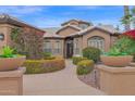 Lush landscaping featuring a curved walkway, potted plants, shrubs and flowers leading to the home's entrance at 16215 W Indianola Ave, Goodyear, AZ 85395