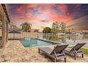 Backyard pool with a view of the serene lake, lounge chairs, and an umbrella for a perfect outdoor retreat at 3121 N Meadow Dr, Avondale, AZ 85392