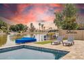 Inviting backyard pool with a view of the lake, includes lounge chairs, a boat dock, and mature trees at 3121 N Meadow Dr, Avondale, AZ 85392