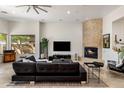 Spacious living room featuring a fireplace, black leather sofa, neutral tile floors, and large windows at 10883 E La Junta Rd, Scottsdale, AZ 85255