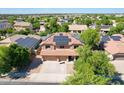 Aerial view of a two story home with a tile roof and solar panels surrounded by a lush green neighborhood at 16626 W Baden Ave, Goodyear, AZ 85338