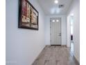 Inviting hallway showcasing wood-look tile flooring, complemented by neutral wall paint, artwork and white doors at 16868 W Earll Dr, Goodyear, AZ 85395
