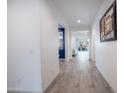 Bright hallway featuring wood-look tile flooring, leading to the living area, enhanced by recessed lighting at 16868 W Earll Dr, Goodyear, AZ 85395