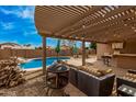 Inviting covered patio boasts a built-in bar, outdoor lighting, a cozy fire pit, and overlooks the refreshing pool at 1917 S Rock Ct, Gilbert, AZ 85295