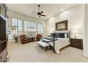 Spacious bedroom featuring a ceiling fan, neutral carpet, natural lighting, and two leather chairs at 10999 E Acoma Dr, Scottsdale, AZ 85255