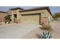 Inviting home exterior with a large two car garage, desert landscaping, and stone accents at 17662 W Cedarwood Ln, Goodyear, AZ 85338