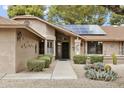 Inviting front entrance with desert landscape, solar panels and a walkway leading to the front door at 20215 N Medallion Ct, Sun City West, AZ 85375