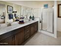 Bright bathroom with double sinks, sleek countertops, a glass-enclosed shower, and ample vanity storage at 41905 W Hospitality Ln, Maricopa, AZ 85138