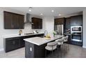 Modern kitchen features stainless steel appliances, dark wood cabinets and island with white quartz countertops at 12219 W Caraveo Pl, Peoria, AZ 85383