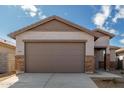 Spacious two-car garage with a brown door, stone accents and a concrete driveway with street number at 17057 W Seldon Ln, Waddell, AZ 85355