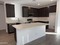 Modern kitchen featuring dark cabinetry, stainless steel appliances, and a spacious center island at 17057 W Seldon Ln, Waddell, AZ 85355