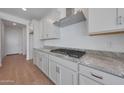 Modern kitchen with stainless steel hood vent and cooktop, granite countertops, and ample cabinet space at 17445 W Via Dona Rd, Surprise, AZ 85387